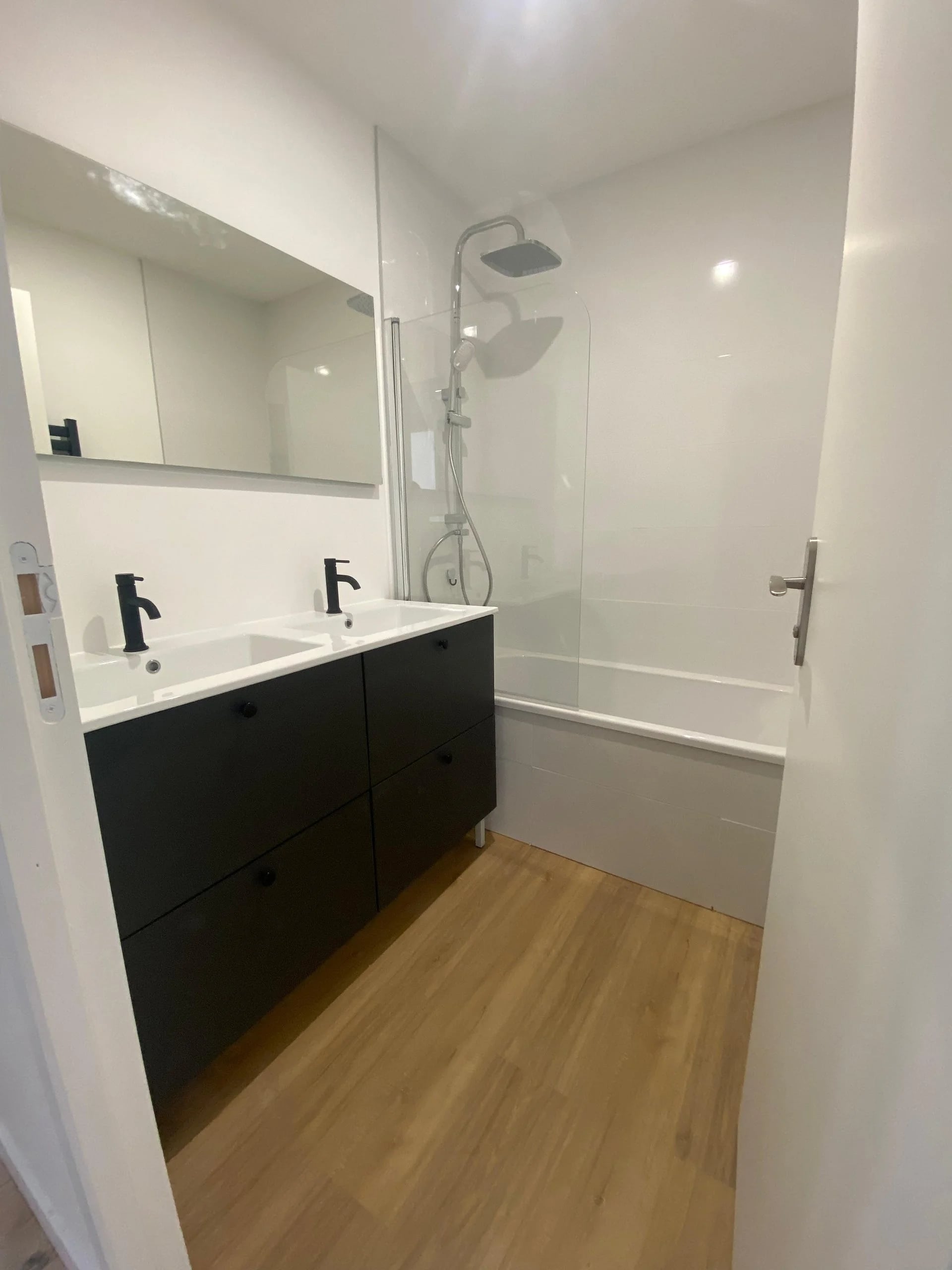 Salle de bain rénovée avec double vasque noire et parquet dans un appartement à Nantes